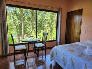 1 dormitorio con cama, mesa, sillas y ventana en Rancho San Miguel en Villa del Carbón