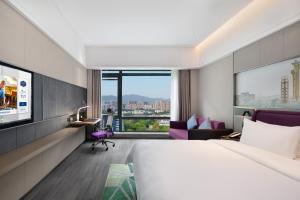ein Hotelzimmer mit einem Bett und einem TV in der Unterkunft Hampton by Hilton Beijing South Railway Station in Peking