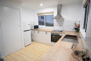 uma cozinha com armários brancos e um frigorífico branco em Port Campbell Motor Inn em Port Campbell