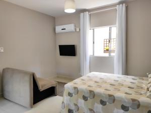 een slaapkamer met een bed, een stoel en een raam bij Residencial Barceloneta in Florianópolis