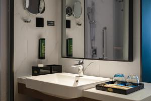a bathroom with a white sink and a mirror at Hampton by Hilton Beijing South Railway Station in Beijing