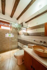 a bathroom with a toilet and a glass shower at Casa de las Flores in Villa de Leyva