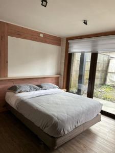 Un dormitorio con una cama grande y una ventana en QUELEN AUSTRAL, en Hornopirén
