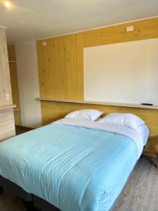 1 dormitorio con 1 cama grande con sábanas azules y almohadas blancas en QUELEN AUSTRAL en Hornopiren