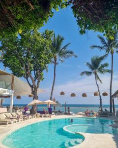 een zwembad op het strand met palmbomen en de oceaan bij Elephant Beach Club & Resort Samui in Chaweng Beach