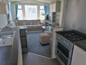 a kitchen and living room with a stove and a couch at Seaside Delight - Close to the beach in Kent