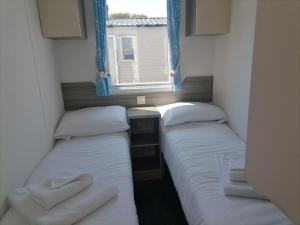 two beds in a small room with a window at Seaside Delight - Close to the beach in Kent