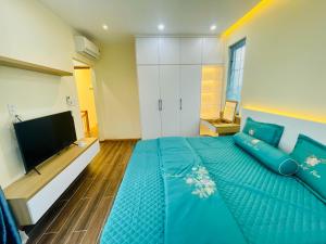 a bedroom with a blue bed and a flat screen tv at Ocean Villa Novaworld Phan Thiết in Bình Tú