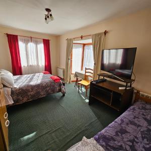 a hotel room with two beds and a flat screen tv at Casa de familia in Ushuaia
