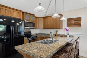 La cuisine est équipée d'un évier et d'un réfrigérateur noir. dans l'établissement The Plantation at Princeville 222 condo, à Princeville