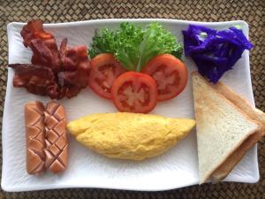 a plate of food with bacon tomatoes and bread at BC Summer Beach in Pran Buri