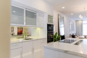 a white kitchen with white cabinets and appliances at The RIYAZ Lavanya in Pantai Cenang