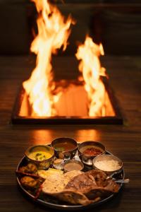 a tray of food on a table in front of a fireplace at Cottages @ Village in Bhīm Tāl