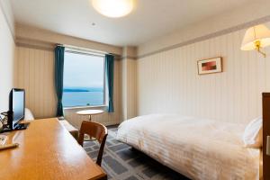 Habitación de hotel con cama, escritorio y ventana en Hotel Welview Kagoshima, en Kagoshima