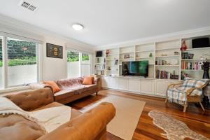 a living room with a couch and a tv at Holley House in Leura