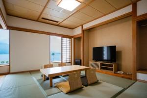 a living room with a table and a flat screen tv at Hotel Welview Kagoshima in Kagoshima