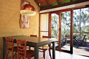 una sala da pranzo con tavolo e sedie di Corymbia Cottage Brokes Secluded Escape for max 4 a Broke
