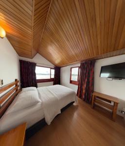 een slaapkamer met een groot bed en een flatscreen-tv bij Hotel Refugio Santa Ines in Aquitania