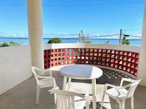 uma mesa e cadeiras numa varanda com vista para o oceano em ビーチサイドペンションみーばる em Nanjo