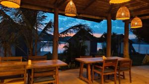 a patio with tables and chairs and a view of the ocean at Sunset Nam Ngum resort in Vang Vieng