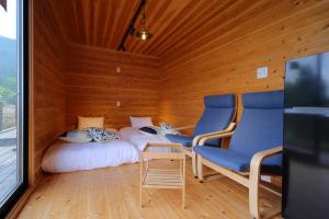 pokój z 2 łóżkami i 2 krzesłami w obiekcie おそとのてらす　南アルプス w mieście Minami Alps