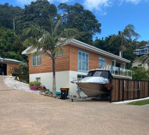 a boat parked next to a house with a palm tree at Tairua Dream in Tairua