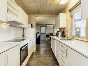 a kitchen with white cabinets and a wooden ceiling at 8 person holiday home in V ggerl se in Marielyst