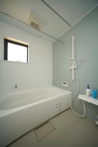 a white bathroom with a tub and a window at BHOLIC（ビーホリック） in Shimonoseki