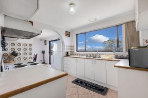 Una cocina con gabinetes blancos y una ventana grande. en Harmony, en Lakes Entrance