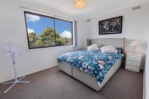 1 dormitorio con 1 cama, ventana y ventilador en Harmony, en Lakes Entrance