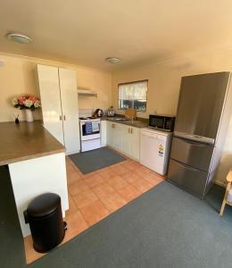 a kitchen with white cabinets and a stainless steel refrigerator at Tairua Dream in Tairua