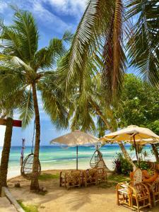 eine Gruppe von Stühlen und Sonnenschirmen am Strand in der Unterkunft On Board Panglao Beach Hostel & Resort in Dao