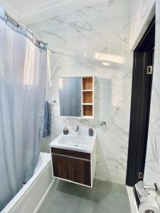 アクラにあるMankatiwa Court Apartmentsの洗面台、浴槽、鏡のあるバスルーム