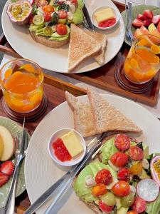 two plates of food with sandwiches and fruit and juice at Mont Goei Pai in Pai