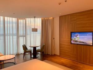 een hotelkamer met een tv en een tafel en stoelen bij Panoramic sea homestay in Ha Long