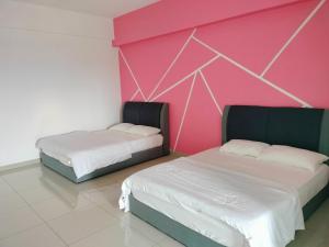 duas camas num quarto com uma parede rosa em Travelers HomestySitiawan b-30-6 The Venus Aparment em Seri Manjung