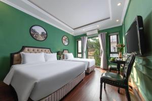 a green bedroom with two beds and a tv at Madelise Adora Hotel & Travel in Hanoi