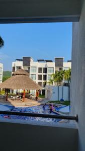 uitzicht op een zwembad met een rieten parasol bij Manzanillo Depto. ¡buena vibra! in Manzanillo