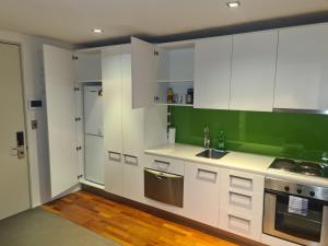 a kitchen with white cabinets and green walls at Boutique Hotel Complex Apartment with Hot Tub, Pool & Gym in Wellington