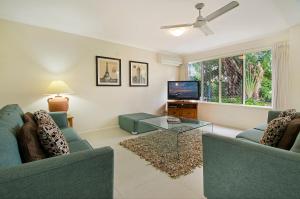 Sala de estar con 2 sofás azules y TV en Ivory Palms Resort Noosa en Noosaville