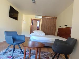 um quarto com uma cama, 2 cadeiras e uma mesa em AU JASMIN DE NUIT em La Plaine des Palmistes