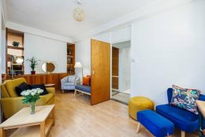 een woonkamer met een gele bank en blauwe stoelen bij Kings Cross Suite in Londen