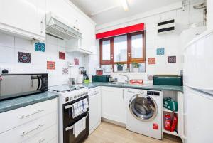 een witte keuken met een wasmachine en een wasmachine bij Kings Cross Suite in Londen