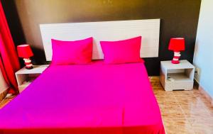 a bedroom with a large pink bed with two red lamps at Sonnige Ferienwohnung mit Wifi in Flic-en-Flac +69 photos