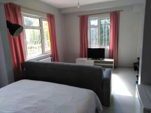 1 dormitorio con 1 cama y 2 ventanas con cortinas rojas en RAZI TURIZM en Estambul