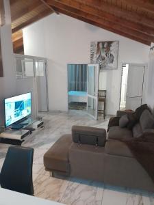 a living room with a couch and a flat screen tv at VillaBadlou "Lodge Ti-Kaco Vanille" in Trois-Rivières