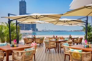 ドバイにあるMarriott Resort Palm Jumeirah, Dubaiのビーチを見渡すテーブルとパラソル付きのレストラン