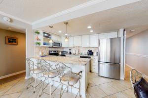 a kitchen with a large counter with chairs and a refrigerator at Golden Sands 618 in Ocean City