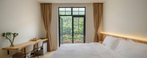 a bedroom with a white bed and a window at La Petronilla Boutique Hotel Moganshan in Deqing