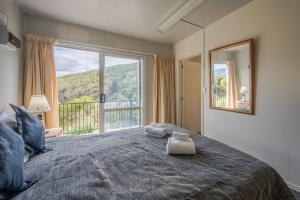 een slaapkamer met een groot bed met een groot raam bij Lushingtons Bay - Takamatua in Akaroa
